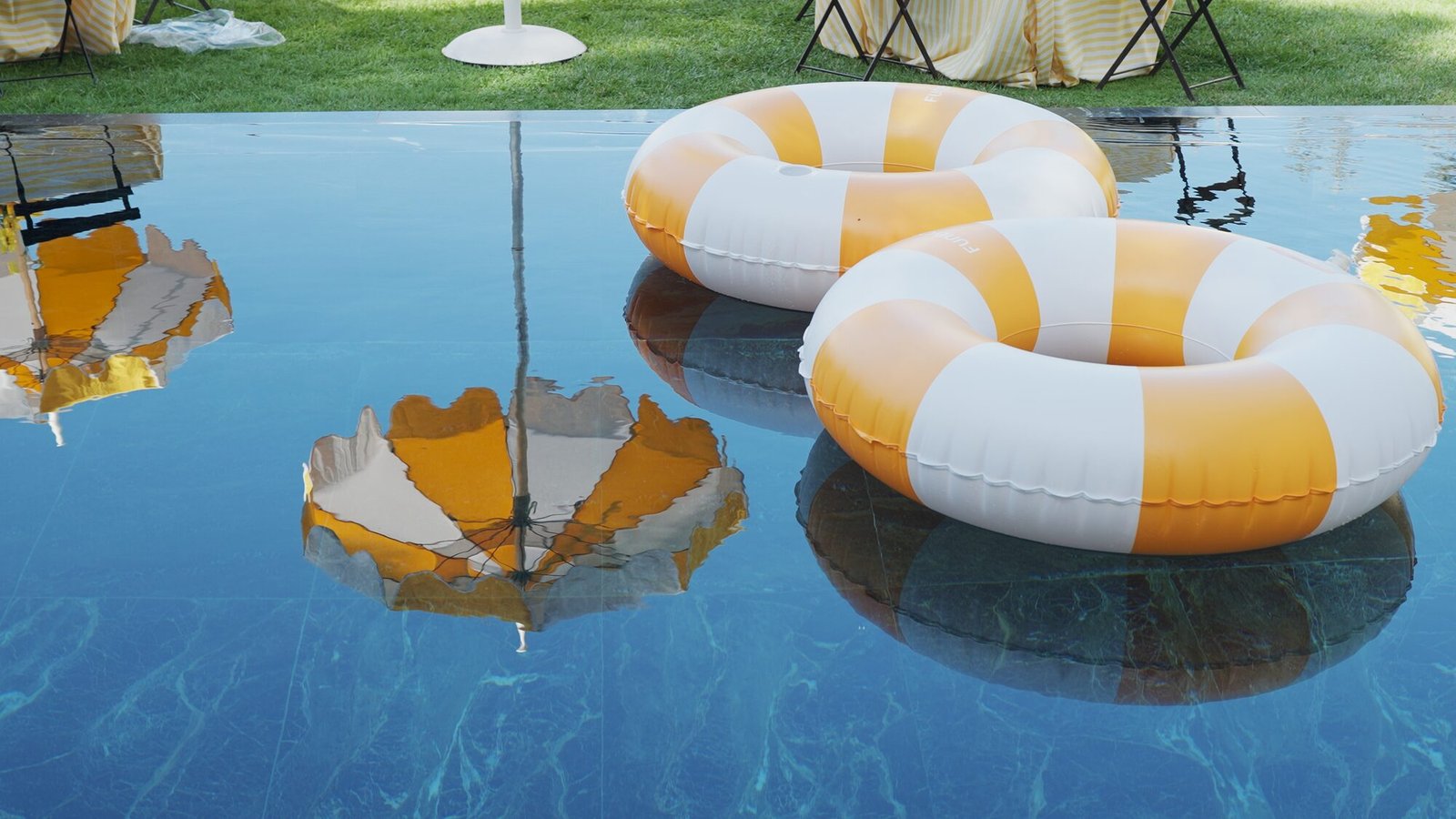 Yellow and white striped pool floats and umbrellas at the poolside wedding brunch at Castello di Vicarello
