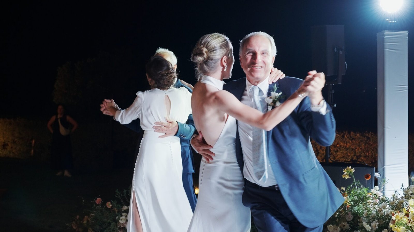 Bride dancing with her father in a blue suit under stage lights during the evening reception at Castello di Vicarello