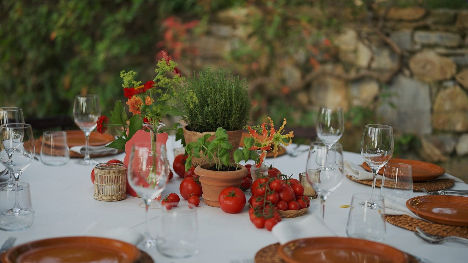 Welcome dinner table at Castello di Vicarello set with fresh tomatoes, basil and terracotta plates for a Tuscan wedding weekend